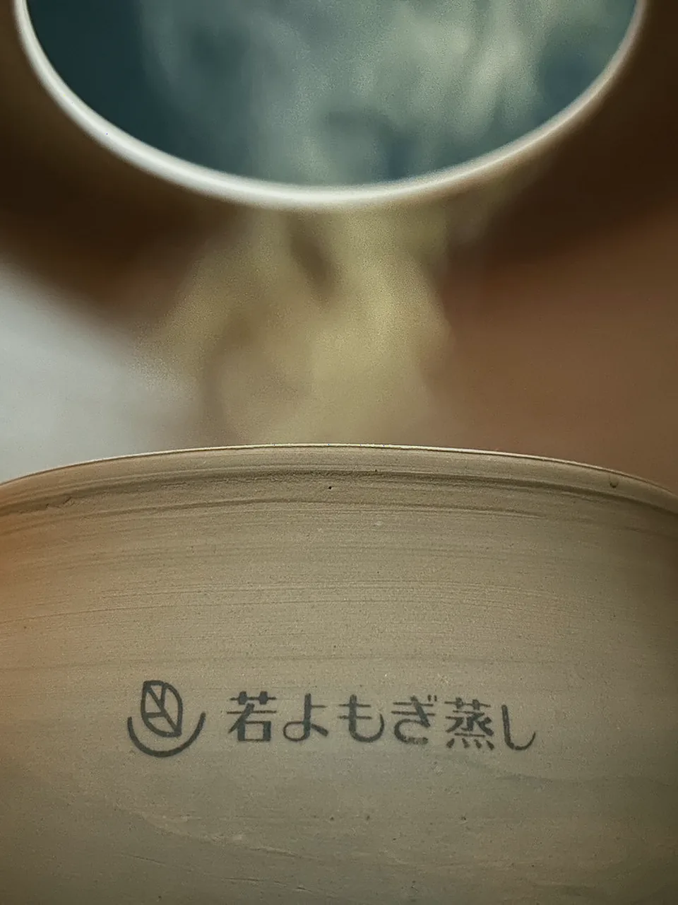 立ち上る蒸気に包まれる若よもぎ蒸しの黄土の壺