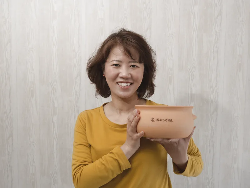 若よもぎ蒸しの壺を手にするスタッフ